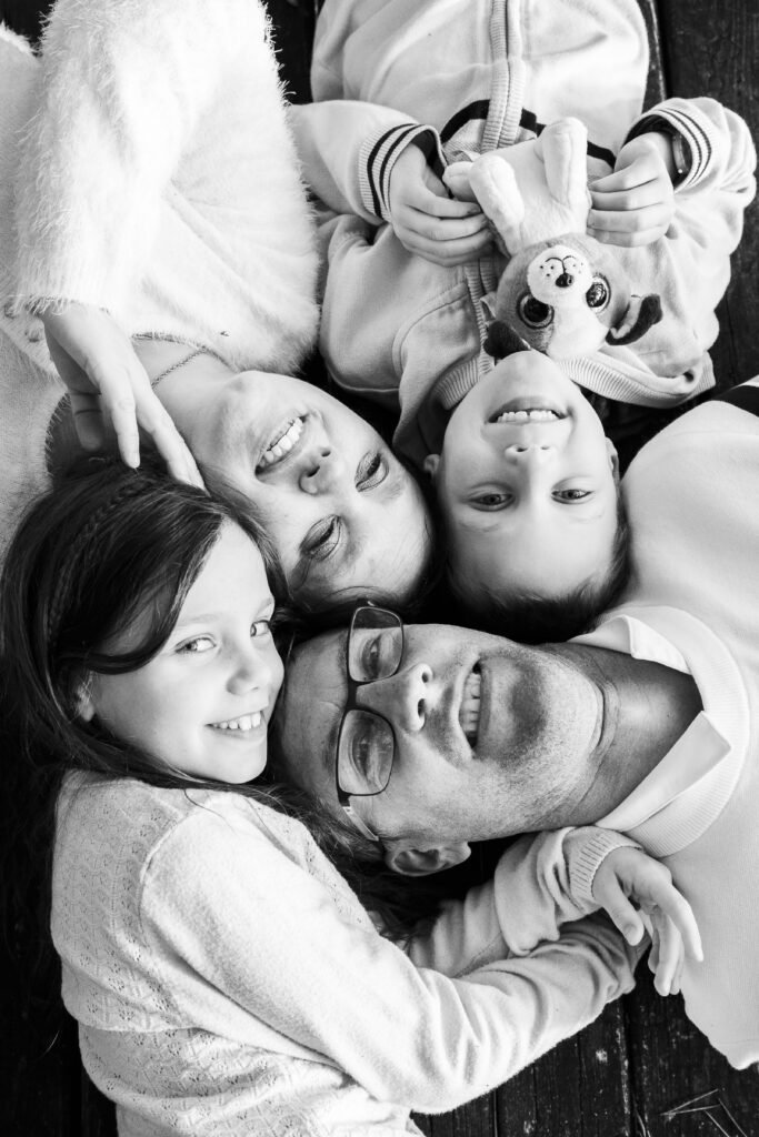 Famille réunie et allongée ensemble lors d’un portrait en noir et blanc