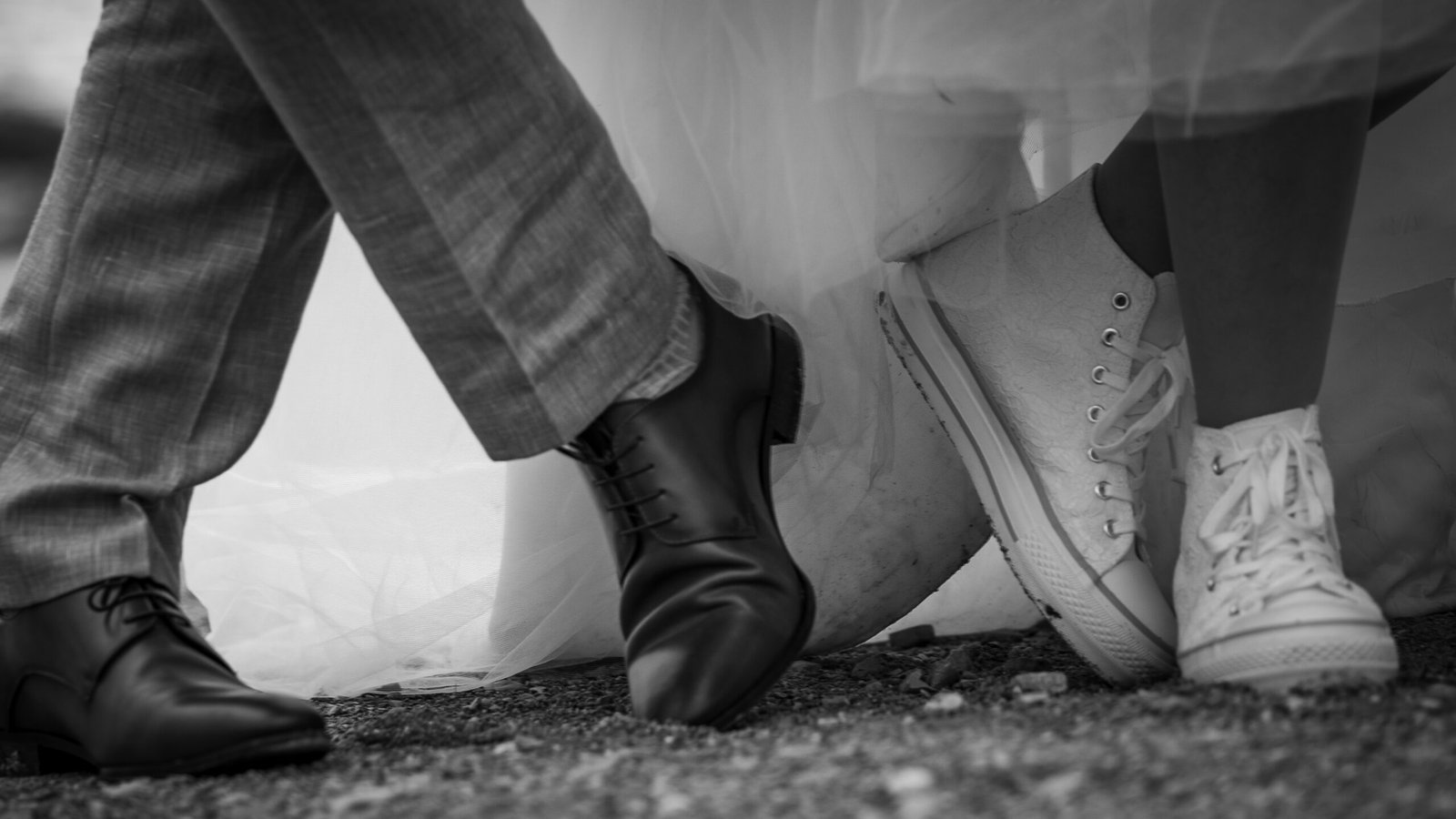Chaussures des mariés sous la robe de mariée en noir et blanc