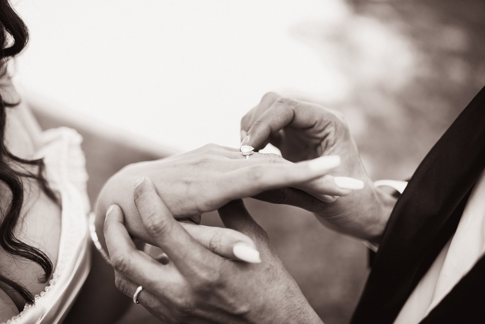 Mains de mariés et alliances en noir et blanc le jour de leur mariage