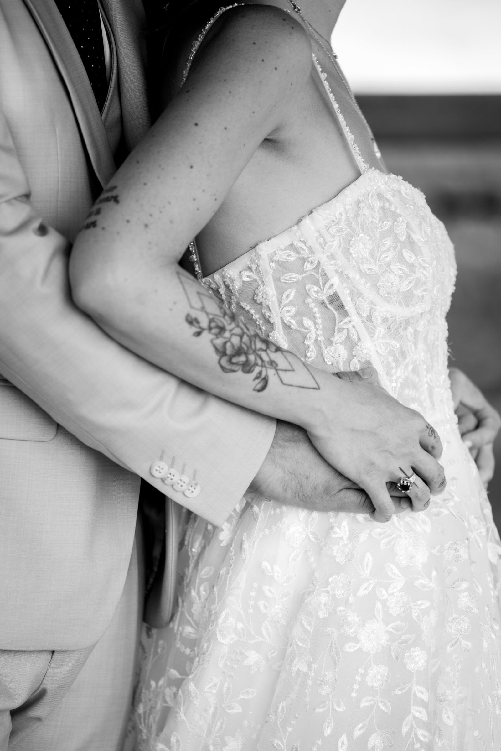 Détail des mains des mariés enlacées sur la robe de mariée lors d’un mariage près de Gaillac.