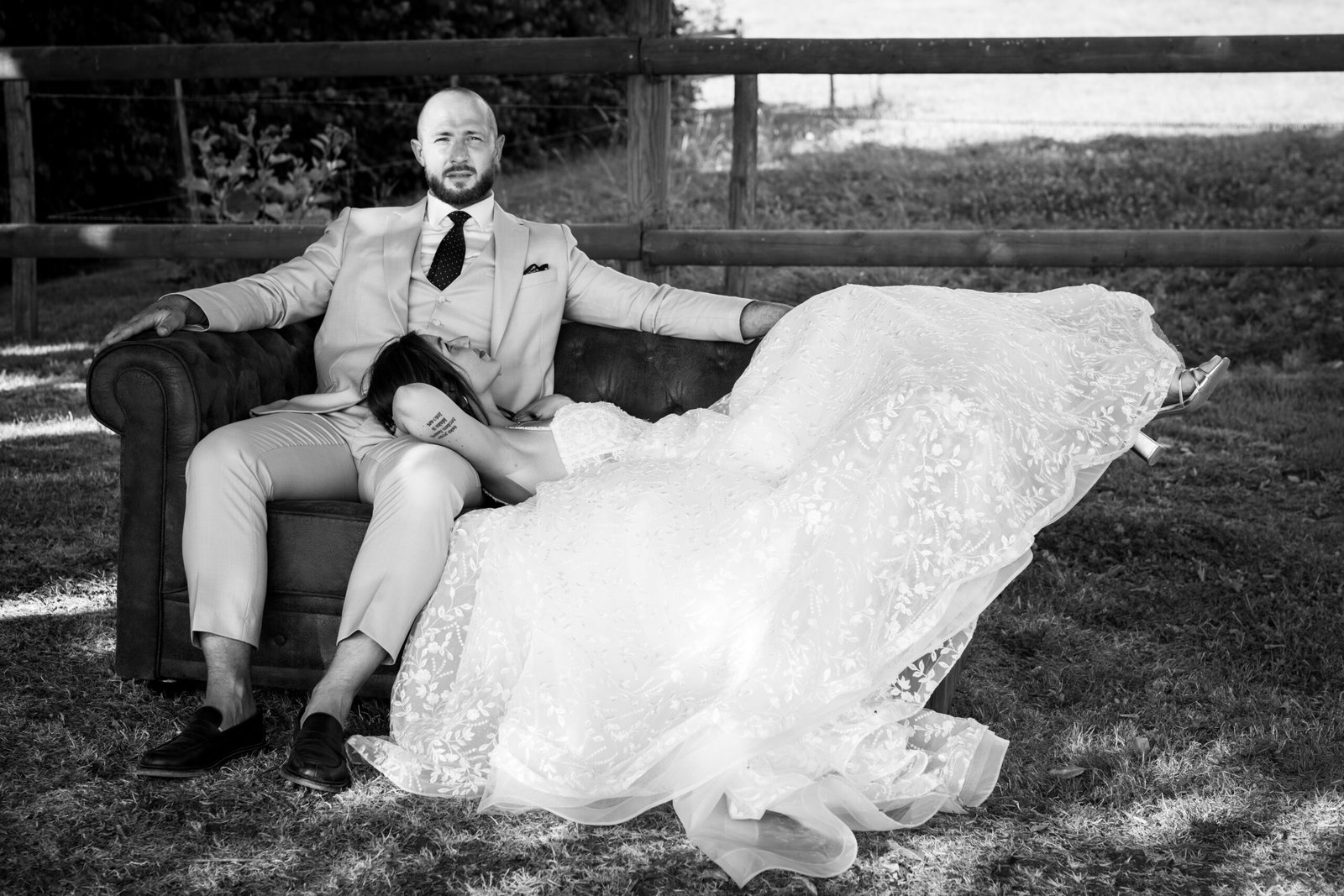 Couple de mariés enlacés sur un canapé en noir et blanc – Alexandra Chabaud Photographe