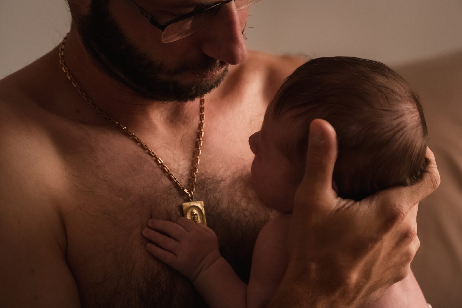 Papa tenant son nouveau-né contre lui lors d’une séance photo naissance